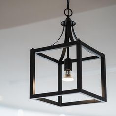 a light fixture hanging from the ceiling in a room with white walls and flooring