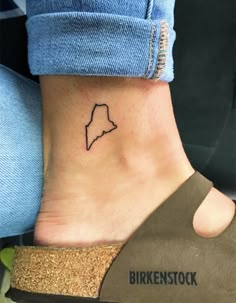 a small tattoo on the ankle of a woman's foot, which is shaped like a map