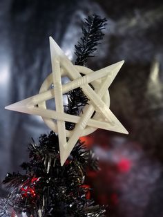 a white star ornament hanging from a christmas tree