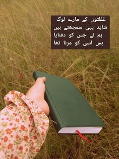 a person holding a book in their hand with an arabic quote on the page above it