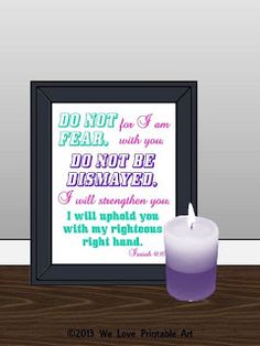 a lit candle sitting next to a framed poster with the words do not fear and do not be dismaved