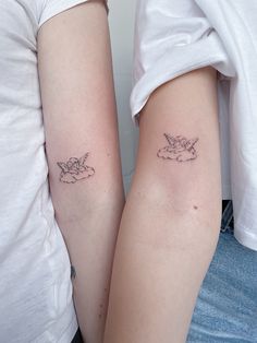 two people with matching tattoos on their arms, one holding the other's arm