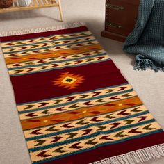 a red and yellow rug on the floor next to a bed with a wooden dresser