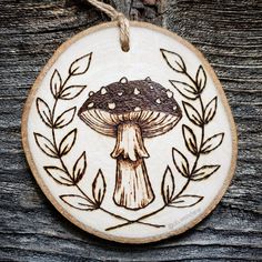 a wooden ornament with an image of a mushroom and leaves on the front