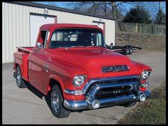 an old red truck parked in front of a building