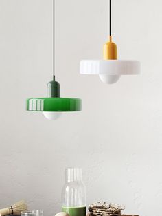 three pendant lights hanging from the ceiling above a table with food and drinks on it