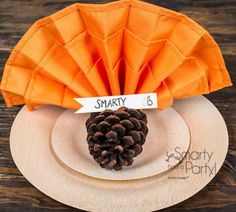 there is a small pine cone on top of a white plate with an orange napkin