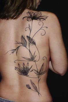 a woman's back tattoo with flowers and leaves on her left side ribcage