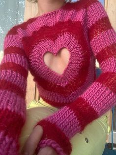 a close up of a person wearing a sweater with a heart cut out on it