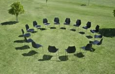 a circle of chairs sitting on top of a lush green field