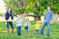 a group of people standing on top of a lush green field with trees in the background