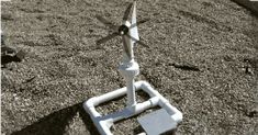 a small wind turbine sitting on top of a grass covered field