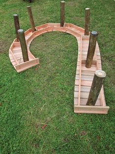 a small wooden bridge made out of wood sticks and logs in the grass with two poles sticking out of it