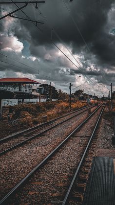 the train tracks are empty and there is dark clouds in the sky