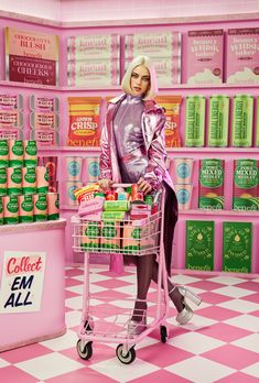 a woman standing in front of a pink store with a shopping cart full of items