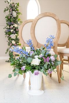 a vase filled with blue and white flowers sitting on top of a table next to two chairs