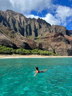 a person swimming in the ocean with mountains in the background