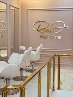 the interior of a hair salon with white chairs and gold trimming on the walls