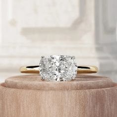 an oval cut diamond ring sitting on top of a wooden stand