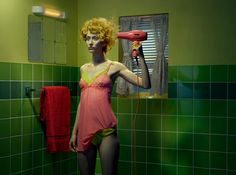 a woman in a pink bathing suit blow drying her hair with a red blow dryer