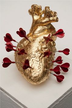 a heart shaped sculpture with red flowers on the bottom and sides, against a white background