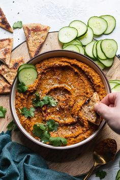 a bowl filled with hummus, cucumber and pita chips