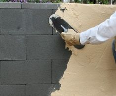 a man is painting the side of a brick wall