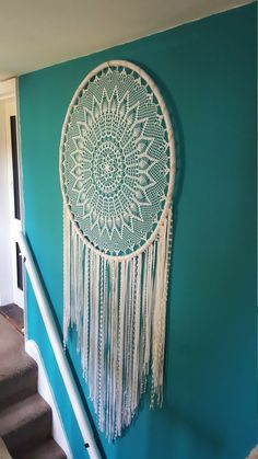 a white dream catcher hanging on the side of a blue wall next to some stairs