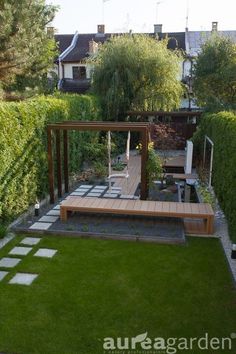 a small garden with wooden benches and green grass in the back yard, surrounded by hedges