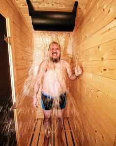 a man standing in a sauna with water coming out of his mouth and arms