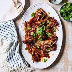 a white plate topped with meat covered in sauce and garnished with cilantro