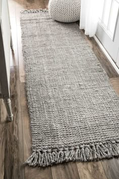 a gray rug with fringes on the floor