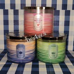 three different colored candles sitting next to each other on a checkered tablecloth background