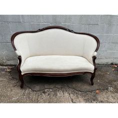 a white couch sitting on top of a sidewalk next to a brick wall in front of a building