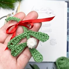 a hand holding an ornament made out of crochet with a red ribbon