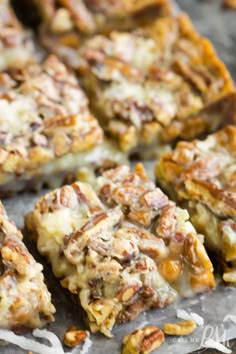 several pieces of dessert sitting on top of a piece of parchment paper with nuts all over it