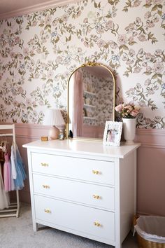 a white dresser sitting next to a wall with a mirror on it's side