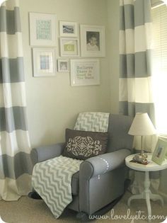 a gray chair sitting in front of a window next to a lamp and pictures on the wall