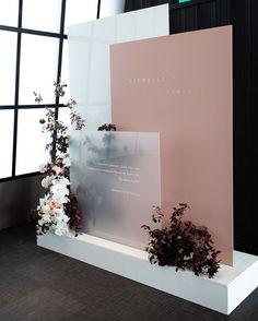 flowers and plants are on display in front of a pink wall with black framed windows