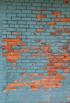 an old blue brick wall with peeling paint and rust on the bricks, as well as a red fire hydrant