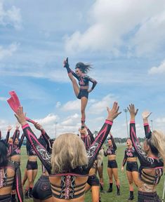 a group of cheerleaders in black and pink outfits are performing on the field