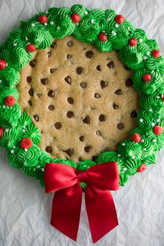 a cookie cake decorated with green icing and red bows