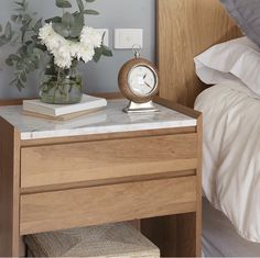 a nightstand with a clock and flowers on it