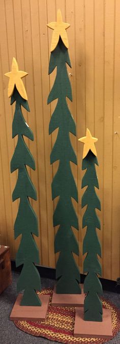 three wooden christmas trees with stars on them in front of a wall and carpeted area