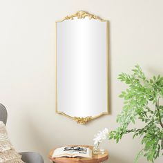 a mirror hanging on the wall next to a table with a book and potted plant