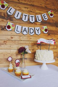 a cake and cupcakes are sitting on a table in front of a sign that says little lady