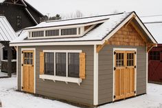 a small shed with two windows on the roof and one door open to let in some snow