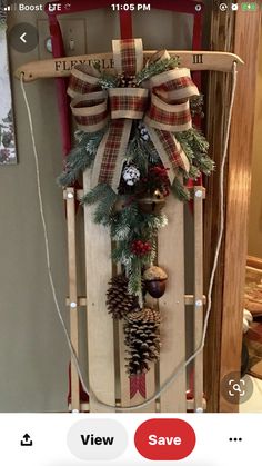 a sled decorated with pine cones, evergreens and other holiday decorations is hanging on the wall