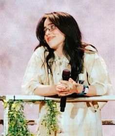 a woman with long black hair holding a microphone