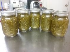 six jars filled with pickles sitting on top of a counter